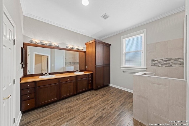 full bath featuring double vanity, crown molding, a sink, and wood finished floors