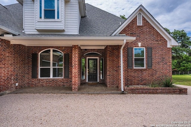 property entrance with brick siding and roof with shingles