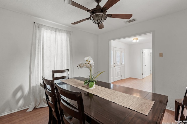 dining room with a ceiling fan, light wood-type flooring, visible vents, and baseboards