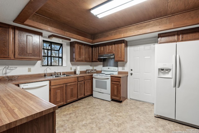 kitchen featuring a tray ceiling, light floors, a sink, white appliances, and under cabinet range hood