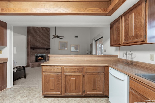 kitchen featuring brown cabinets, a fireplace, light countertops, open floor plan, and white dishwasher