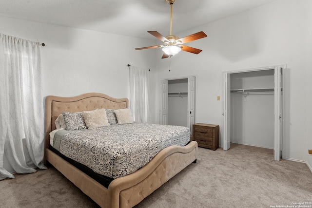 bedroom with ceiling fan, two closets, and light colored carpet