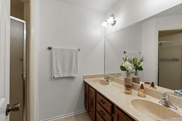 bathroom with double vanity, an enclosed shower, tile patterned flooring, and a sink