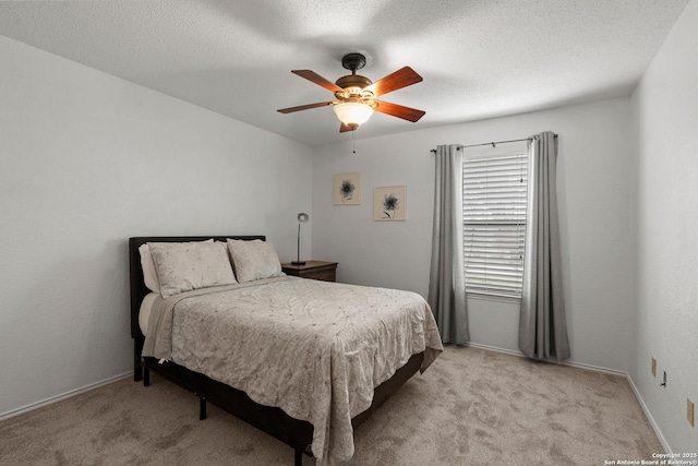 bedroom with light carpet, a textured ceiling, a ceiling fan, and baseboards