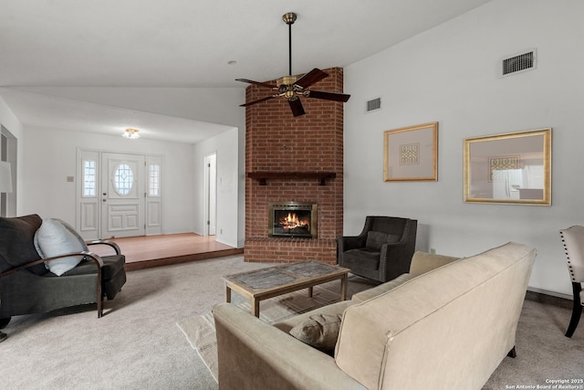 living area featuring light carpet, a fireplace, lofted ceiling, and visible vents