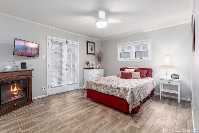 bedroom featuring access to outside, light wood-type flooring, a glass covered fireplace, and crown molding