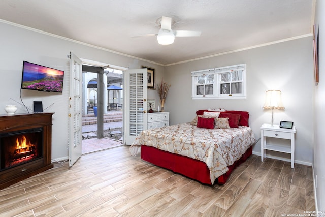 bedroom with access to exterior, crown molding, a lit fireplace, and light wood finished floors