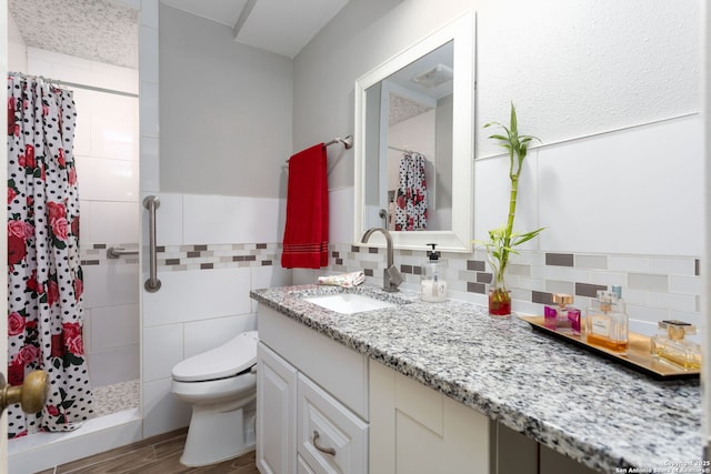 full bath featuring toilet, vanity, tile walls, and a shower stall