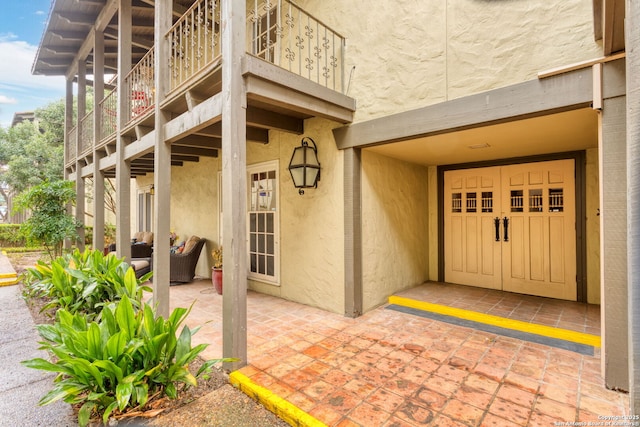 doorway to property featuring a patio, a balcony, and stucco siding