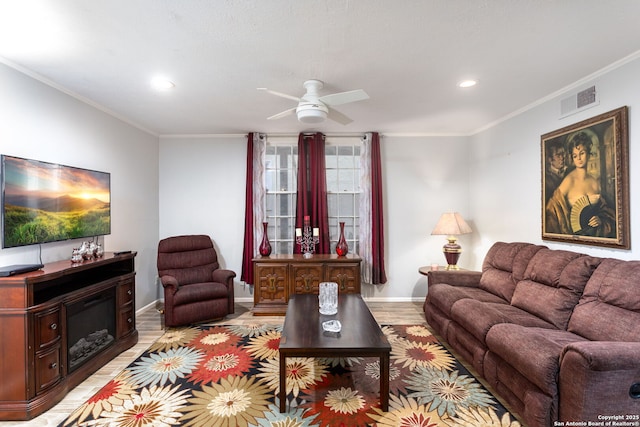 living room with light wood-type flooring, visible vents, crown molding, and a glass covered fireplace