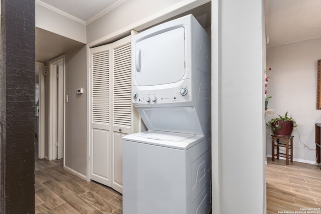 clothes washing area with laundry area, baseboards, ornamental molding, wood finish floors, and stacked washing maching and dryer