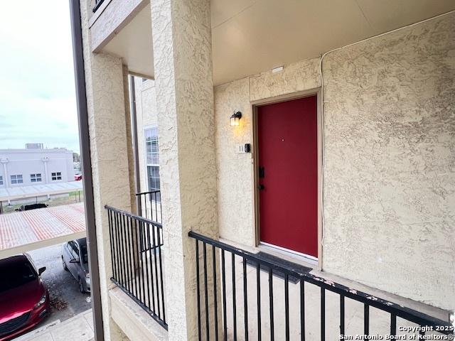 entrance to property with a balcony and stucco siding