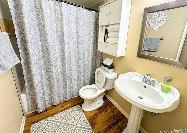 bathroom with toilet, a shower with curtain, baseboards, and wood finished floors