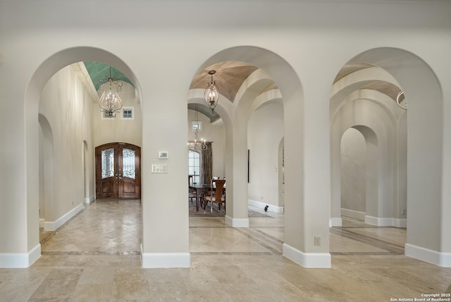 foyer entrance featuring marble finish floor, french doors, baseboards, and an inviting chandelier