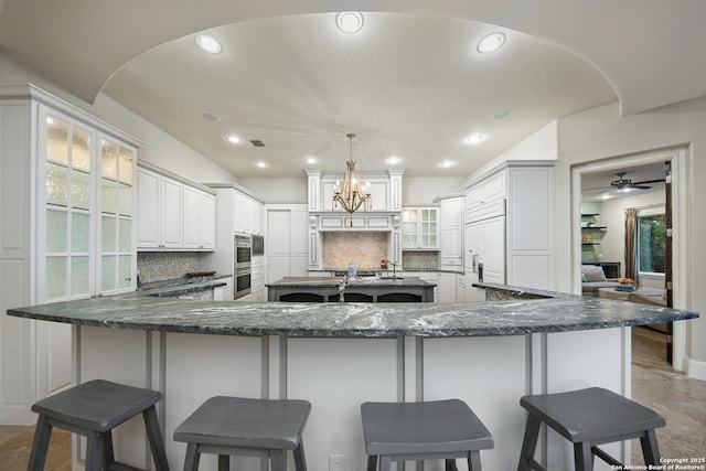 kitchen featuring glass insert cabinets, white cabinetry, paneled refrigerator, and a breakfast bar area