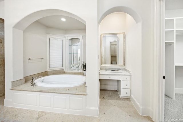 bathroom featuring a garden tub and vanity