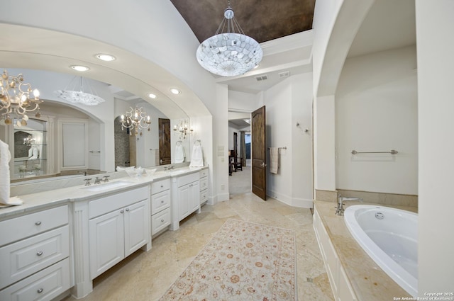 ensuite bathroom with double vanity, an inviting chandelier, ensuite bath, and a sink