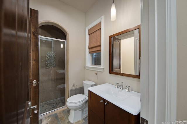 bathroom featuring a stall shower, stone finish flooring, vanity, and toilet