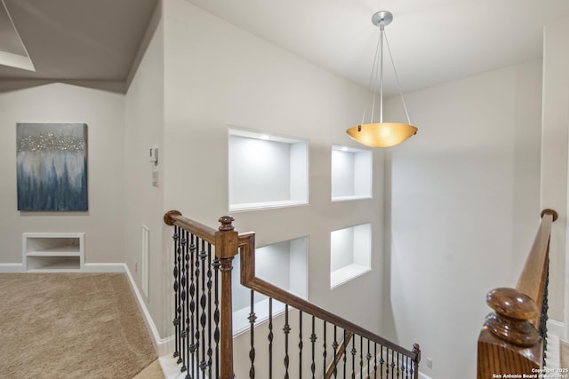 hall with carpet floors, baseboards, and an upstairs landing