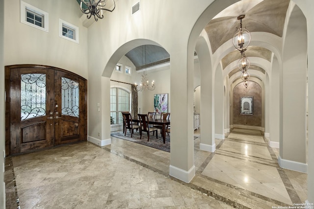 foyer with arched walkways, an inviting chandelier, visible vents, and baseboards