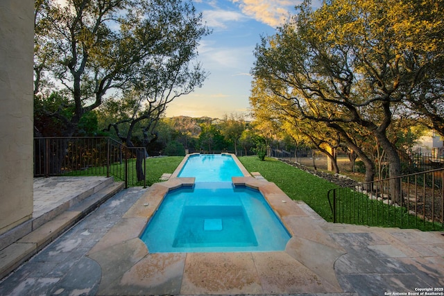 view of swimming pool featuring a pool with connected hot tub, fence, a lawn, and a patio