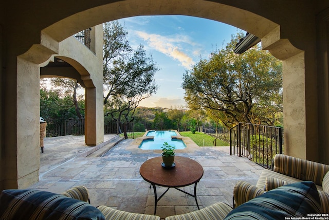 patio terrace at dusk with fence and a fenced in pool