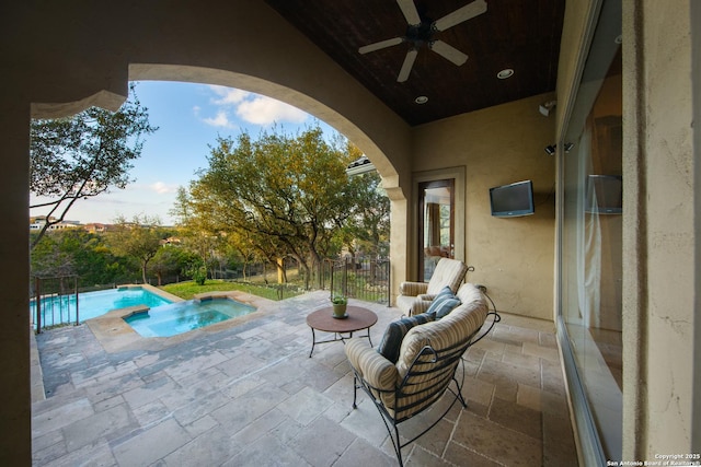 view of patio with a ceiling fan, a pool with connected hot tub, and fence