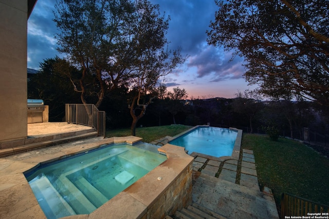 pool at dusk with an outdoor pool, a patio, area for grilling, and an in ground hot tub