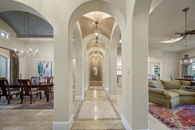 interior space featuring baseboards, arched walkways, a towering ceiling, and an inviting chandelier