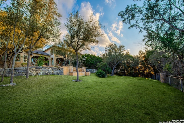 yard at dusk featuring fence