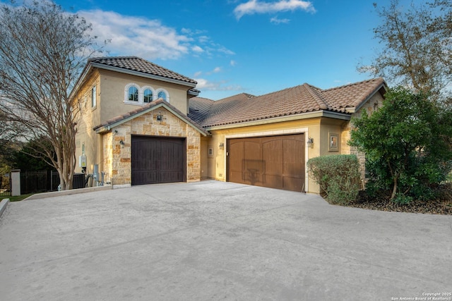 mediterranean / spanish house with a garage, a tile roof, concrete driveway, and stucco siding