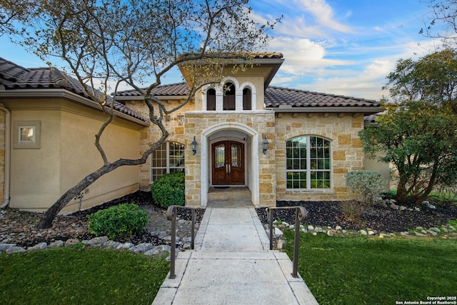 doorway to property with stucco siding, french doors, and a tiled roof