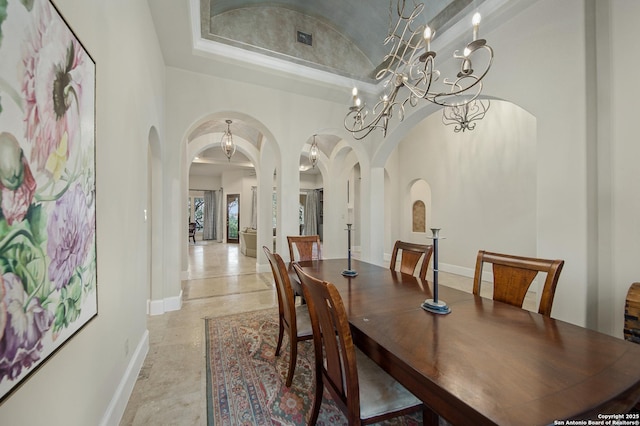 dining space featuring arched walkways, visible vents, vaulted ceiling, and baseboards