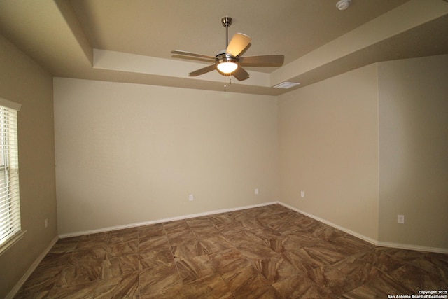 unfurnished room with a ceiling fan, a raised ceiling, visible vents, and baseboards