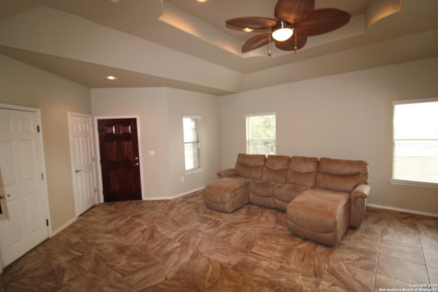 living area featuring a raised ceiling, plenty of natural light, and baseboards