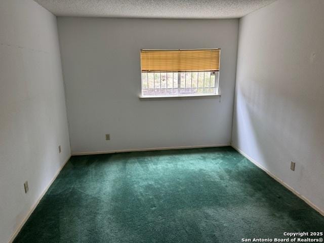 empty room featuring a textured ceiling and dark carpet