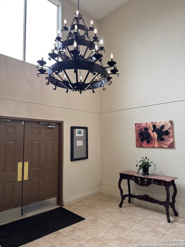 entryway with a high ceiling, baseboards, and a chandelier