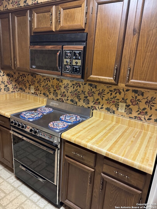 kitchen featuring light countertops, electric range, dark brown cabinets, and wallpapered walls