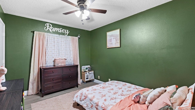 bedroom featuring a textured ceiling, baseboards, a ceiling fan, and light wood-style floors