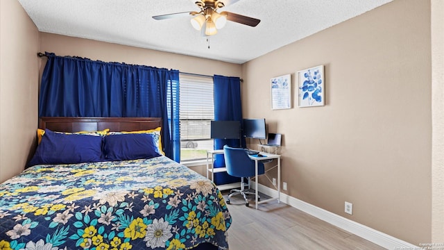 bedroom with a textured ceiling, ceiling fan, wood finished floors, and baseboards