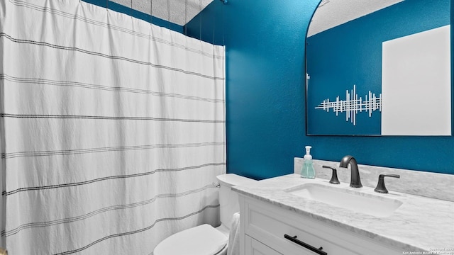 bathroom with toilet, a textured wall, and vanity