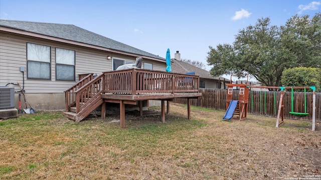 back of property featuring a playground, a yard, central air condition unit, fence, and a deck