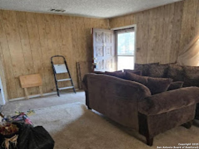 living room with wood walls, visible vents, and a textured ceiling