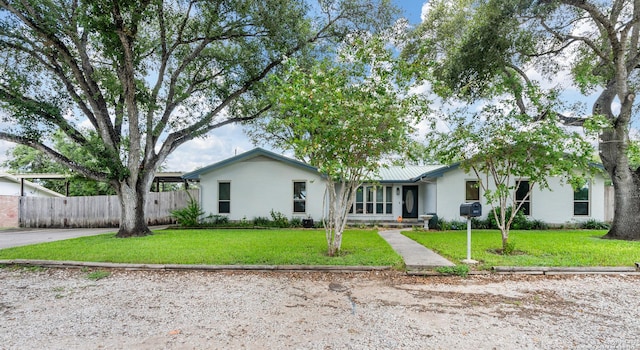 view of front facade featuring metal roof, fence, and a front lawn