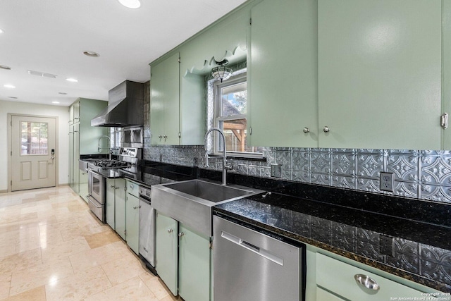 kitchen featuring visible vents, appliances with stainless steel finishes, range hood, dark stone counters, and green cabinetry