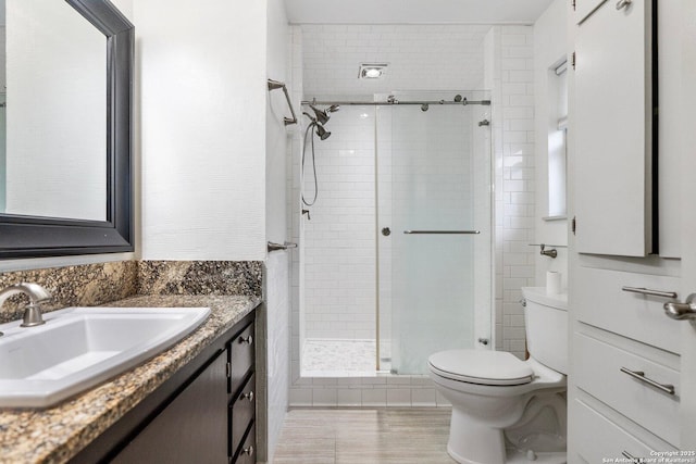 bathroom with toilet, a stall shower, and vanity