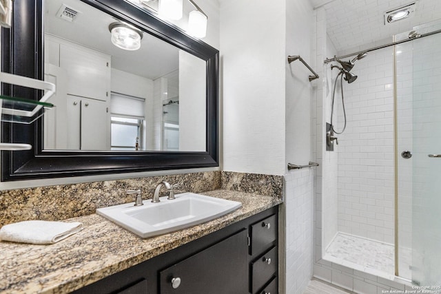 bathroom featuring visible vents, a stall shower, and vanity