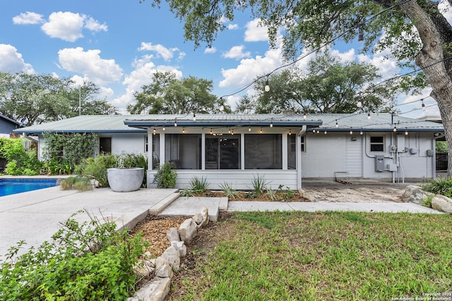 view of front of house featuring a sunroom, an outdoor pool, a patio area, and metal roof