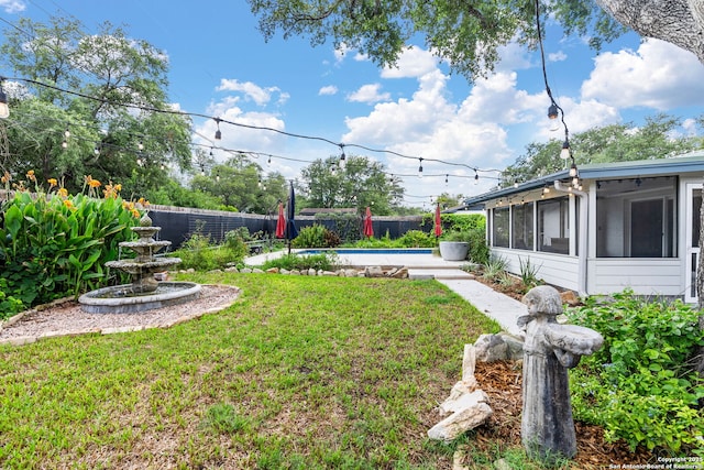 view of yard with a fenced backyard, a sunroom, and a fenced in pool