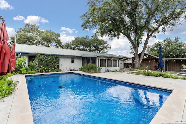 outdoor pool with a sunroom, fence, and a patio